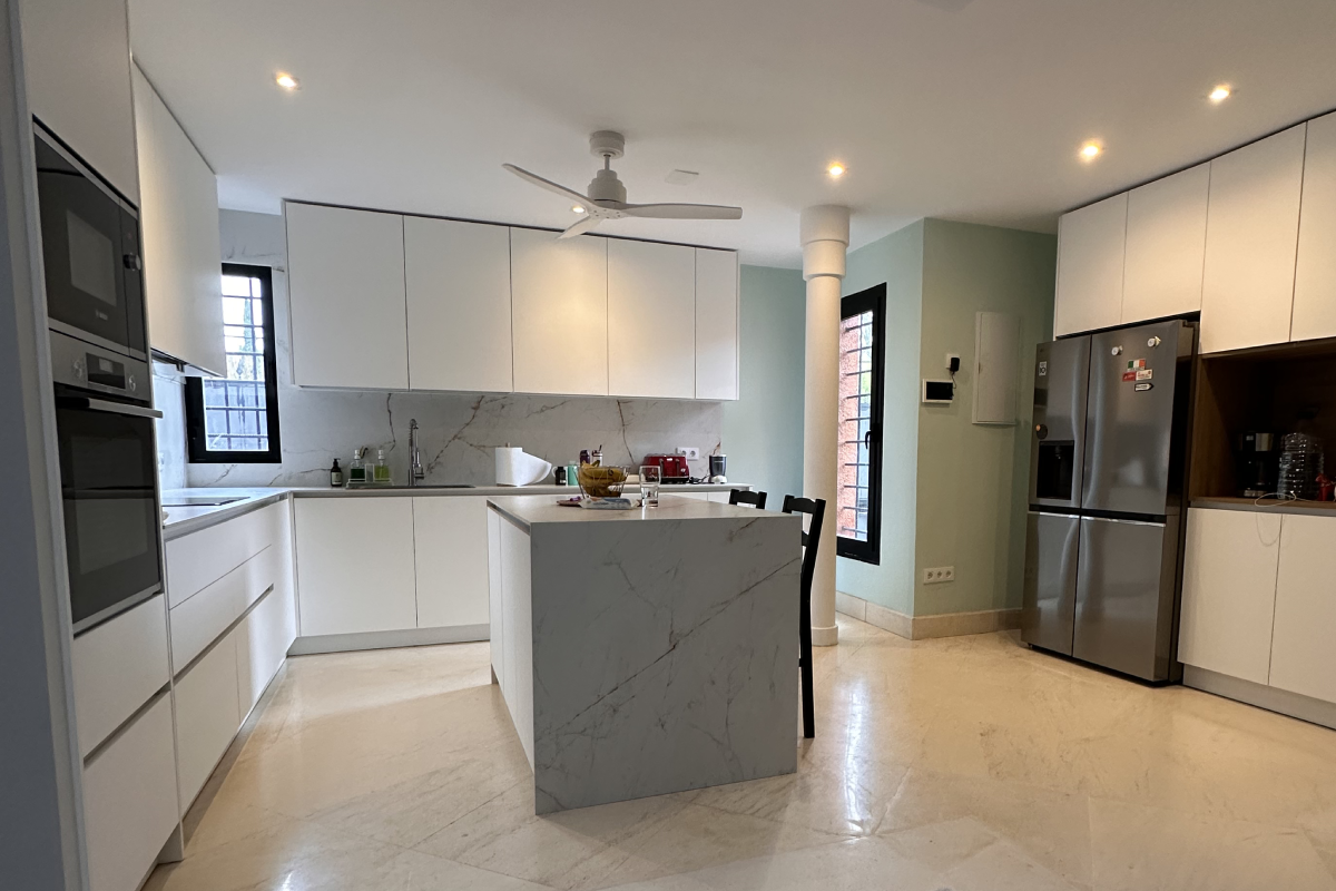 Cocina reformada con isla central y mobiliario blanco